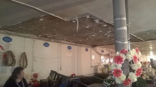 Bucată de tavan, desprinsă din cea mai mare piaţă din Ploieşti; administraţia a pus găleţi în care să se scurgă apa - FOTO