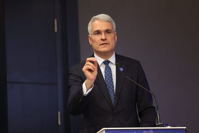 Dragoș Pîslaru vorbind la conferință despre reforma pensiilor magistraţilor și impactul asupra fondurilor PNRR, cu sigla Curții Constituţionale în fundal. | sursa foto: News.ro