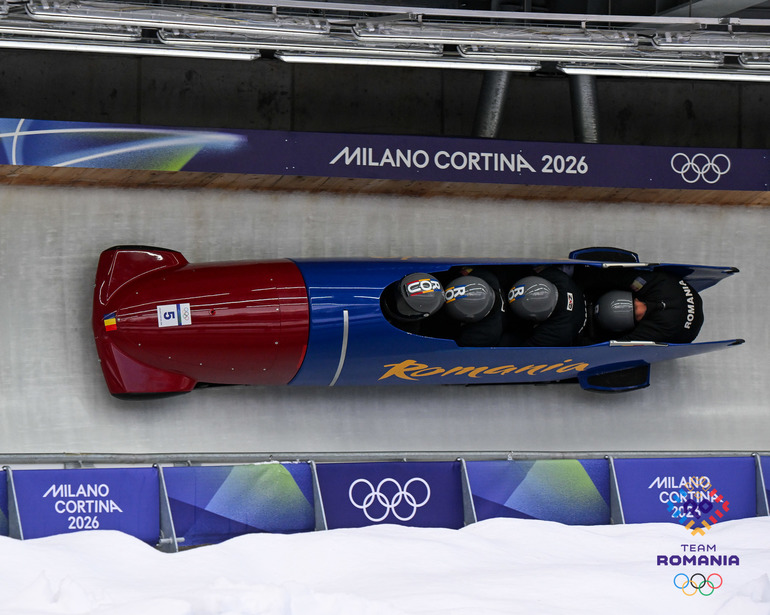 Echipajul României de bob patru persoane pe pistă în competiția olimpică, în timp ce bobul Austriei răsturnat este vizibil în fundal după accident bob Austria. | sursa foto: News.ro