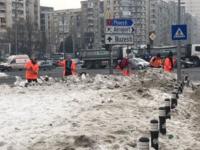 Angajaţii de la salubritate adună zăpada şi gheaţa din jurul sediului Guvernului. FOTO. VIDEO