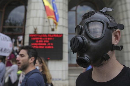 Zeci de persoane, unele cu măşti de gaze, au protestat în faţa Ministerului Mediului, faţă de poluarea din Capitală
