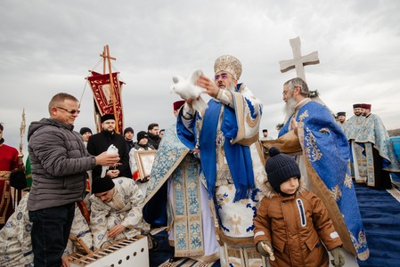 Sute de persoane, la slujba de Bobotează oficială de IPS Ciprian, pe malul râului Buzău/ Crucea aruncată în apă, recuperată de un tânăr - FOTO