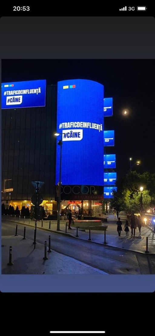 Panou luminos pe care scrie ”trafic de influenţă” şi ”Câine”, aluzie la acuzaţiile aduse lui Nicuşor Dan în campanie, pe magazinul Cocor, chiar vizavi de sediul de campanie al candidatului PNL-USR PLUS / Ciucu:Ce mizerie ilegală! Firea, noaptea ca hoţii