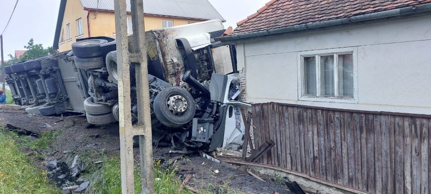 Harghita - Un autocamion a ieşit de pe partea carosabilă şi s-a răsturnat în curtea unui imobil, în Sândominic. Şoferul a rămas încarcerat - FOTO