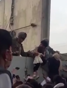 O fetiţă afgană ridicată din mulţime şi preluată de un soldat american peste zidul de securitate al aeroportului din Kabul a devenit imaginea disperării celor care fug din ţară - VIDEO
