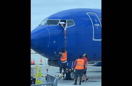 Un pilot de avion se apleacă pe fereastra cabinei pentru a recupera telefonul unui pasager - VIDEO