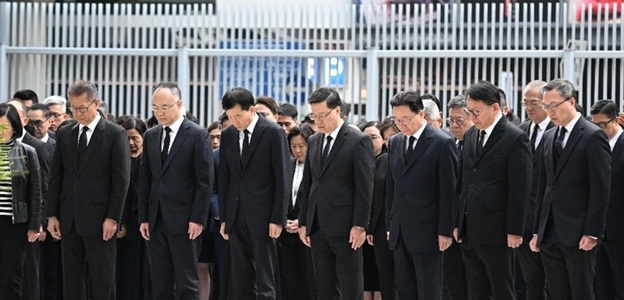 Şeful Executivului din Hong Kong şi miniştri păstrează un moment de reculegere în faţa sediului Guvernului local, după incendiul soldat cu 128 de morţi. Steagurile, coborâte în bernă